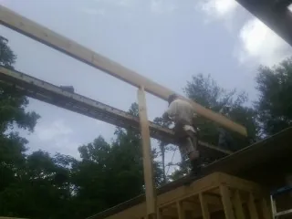 Carpenter setting a ridge beam over a new addition frame — Ice Dam Removal by Roofing Brothers in Muldoon