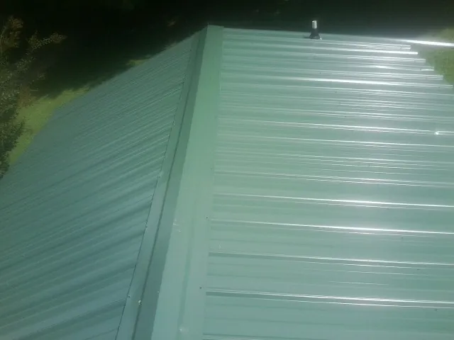 New green metal panels meeting at the ridge of a roof in Muldoon