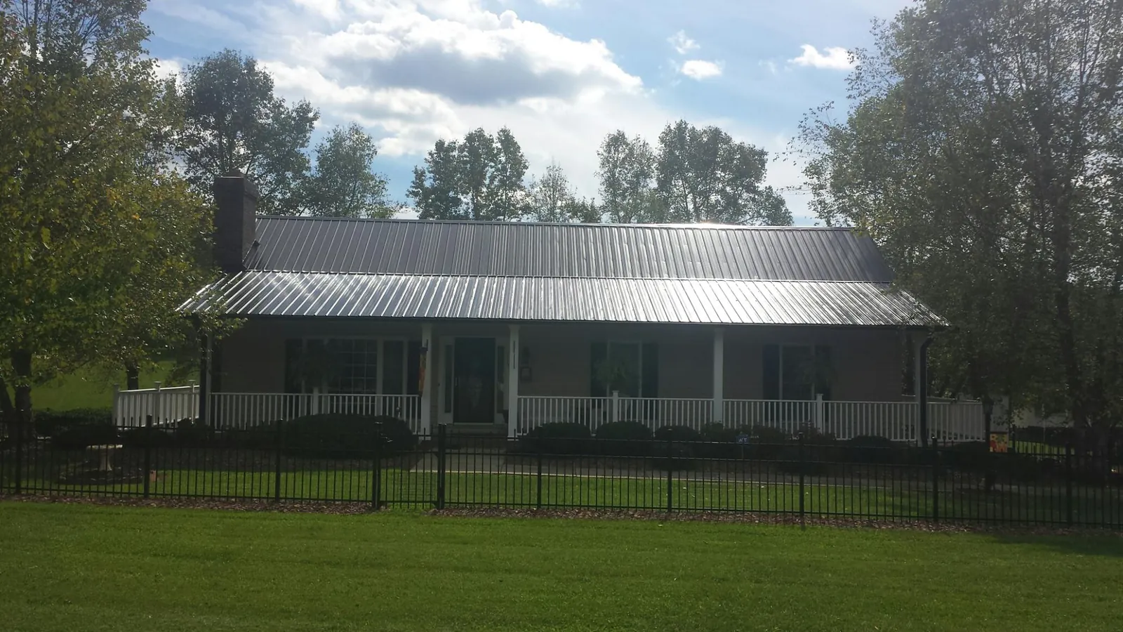 Gray metal roof on a brick ranch with a full width front porch — Gutter Guard Installation work by our crew in Muldoon